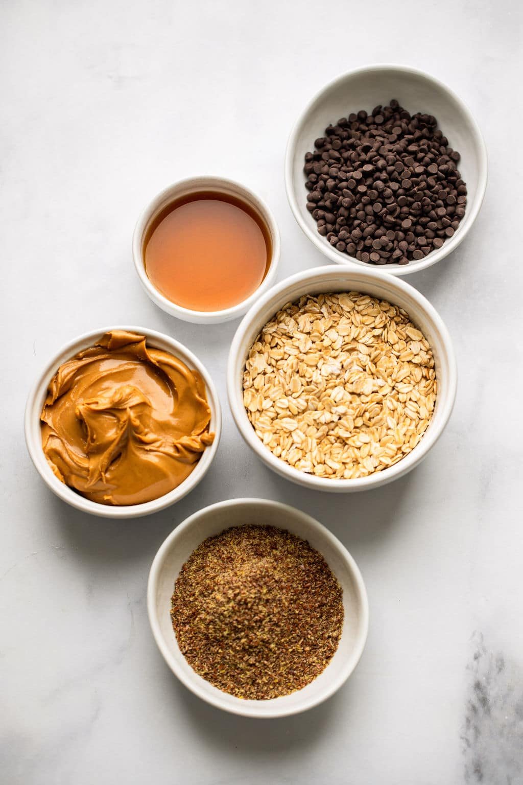 Ingredients for peanut butter butter energy in individual white bowls.