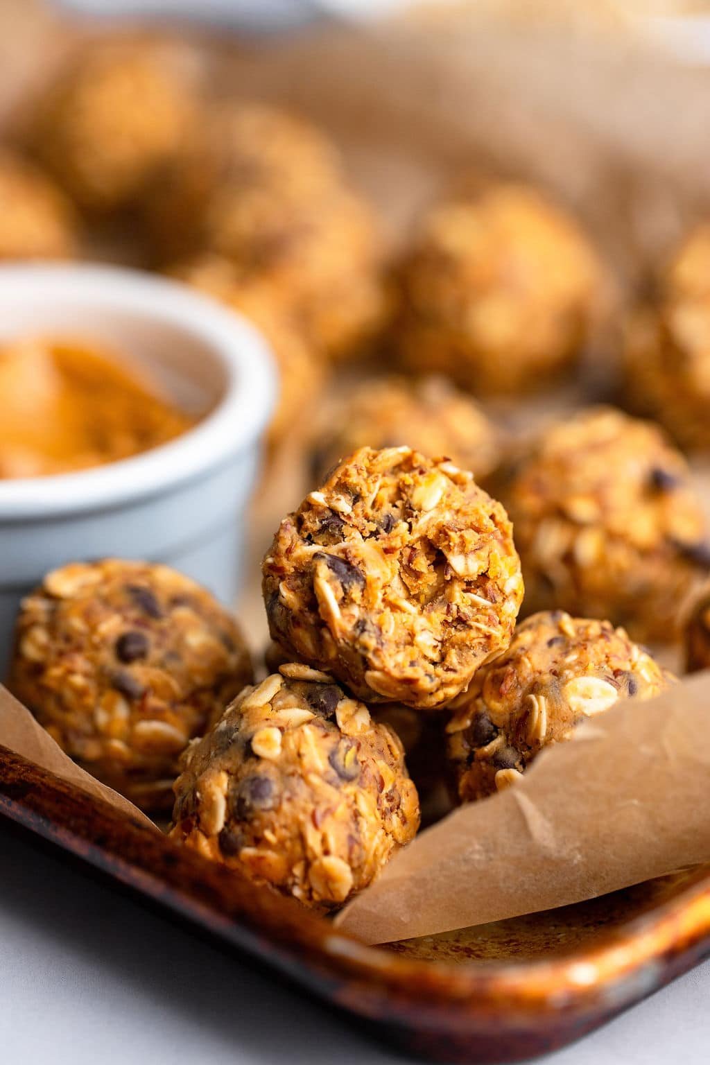 A bowl of peanut butter energy with a bite that runs on a baking sheet lined by parchment.