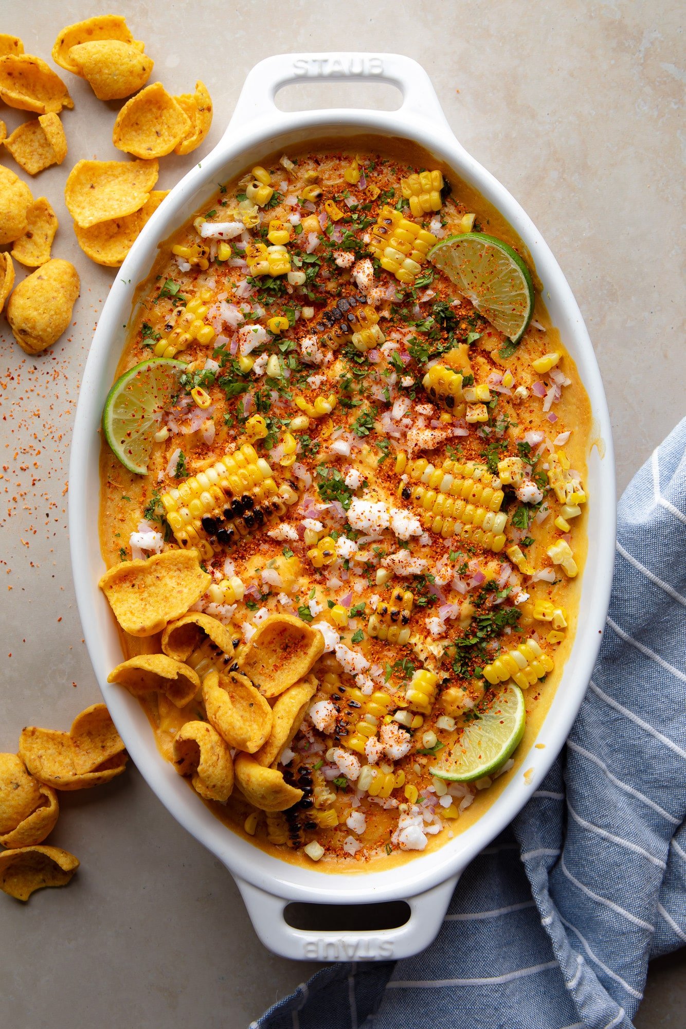 Mexican vegan corn dipped with carbonized corn, fries and lime wedges on a plate.